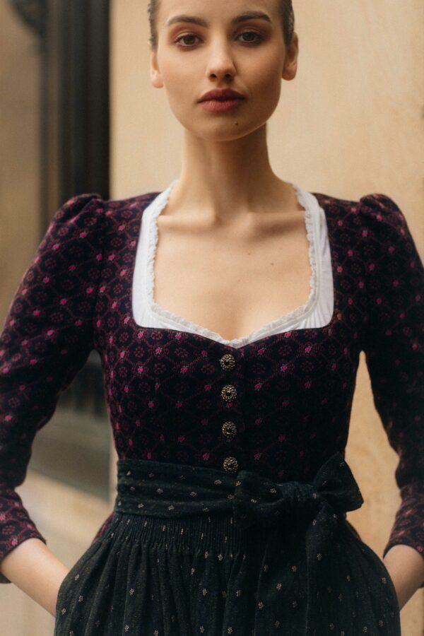 Frauenmodel mit langärmligen Dirndl in rosa/ schwarz und Grüner Schürze