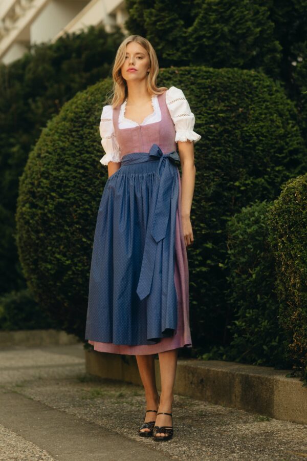 Frauenmodel in rosa Dirndl mit blau gemusterter Schürze und Puffarm Bluse